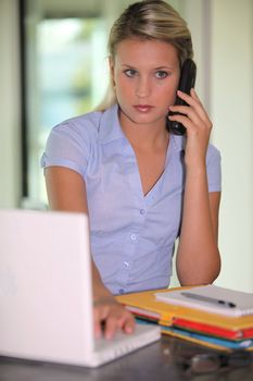 Young woman on the phone, in front of laptop