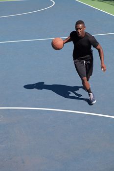 A sweaty young basketball player dribbling down the court demonstrating his ball handling skills.