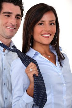 A businesswoman pulling her colleague by the tie.