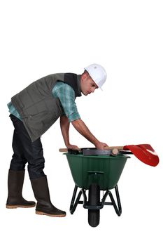 Labourer placing his tools in a wheelbarrow