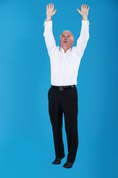 Grey haired businessman reaching into the air