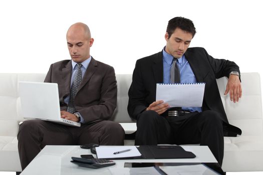 Two determined businessmen sat waiting for presentation