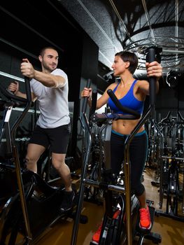 elliptical walker trainer man and woman at black gym training aerobics exercise