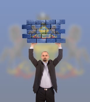 Businessman holding a large piece of a brick wall, flag of Pennsylvania, isolated on national flag