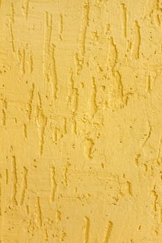 Fragment of a relief plaster walls yellow color closeup as a texture