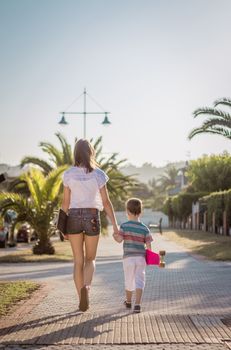 Beautiful young girl and cute kid walking with a skateboards outdoor on summer