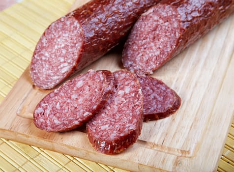 The cut smoked sausage on a wooden board