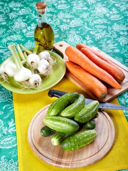 Green cucumbers with onions garlic and carrots on a kitchen table