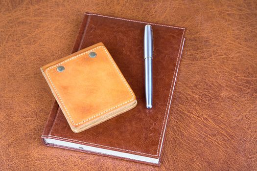 Leather organizers and fountain pen on a textural background