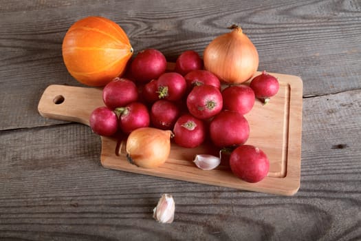 Onions garlic  garden radish on a table from unplaned boards