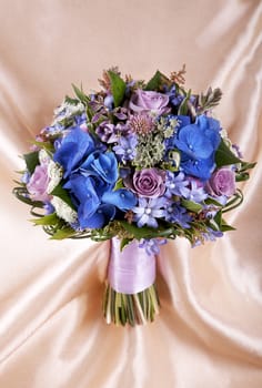 Wedding bouquet of the bride against a golden fabric