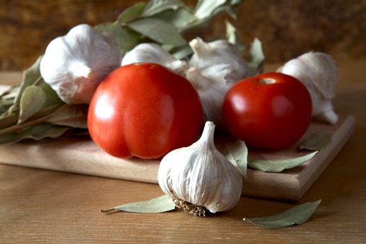 Tomatoes garlic and bay leaf branches on a kitchen table