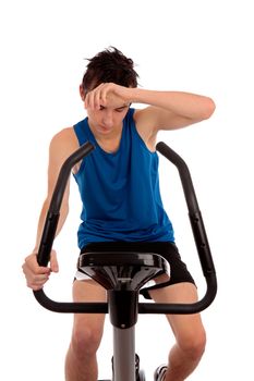 Male teenager wiping brow exhausted after fitness workout on an exercise bike.  White background,