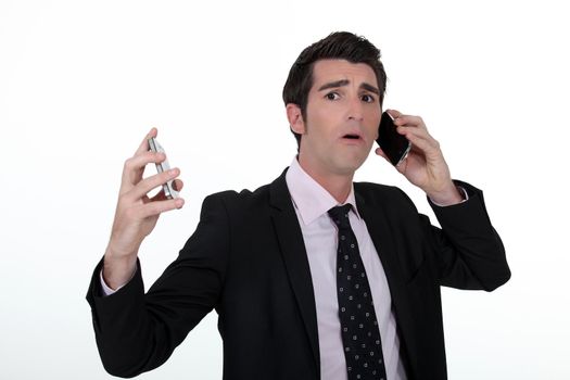 Overwhelmed businessman answering telephones