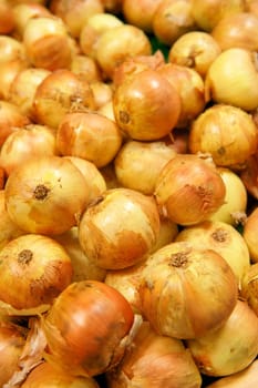 Yellow onions in a pile at a grocery store.