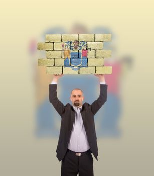 Businessman holding a large piece of a brick wall, flag of New Jersey, isolated on national flag