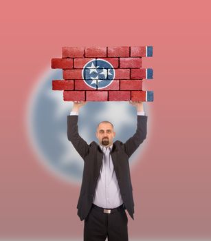 Businessman holding a large piece of a brick wall, flag of Tennessee, isolated on national flag