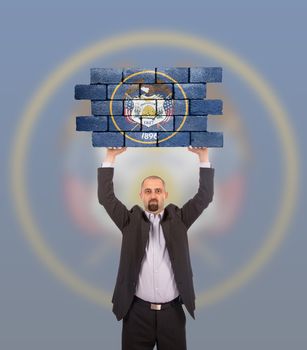 Businessman holding a large piece of a brick wall, flag of Utah, isolated on national flag