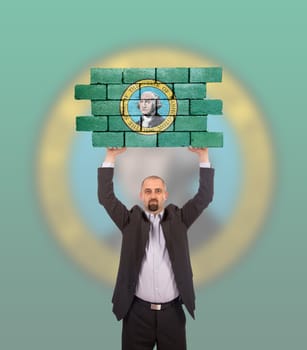 Businessman holding a large piece of a brick wall, flag of Washington, isolated on national flag
