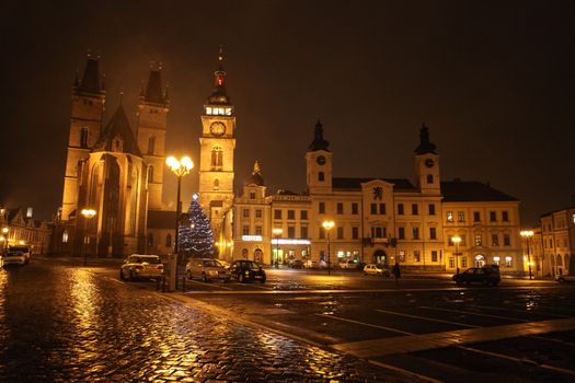 Hradec Králové, the Czech Republic - January 03, 2013: View at the Velké náměstí (Great Square), main old town square in the Czech Republic city of Hradec Králové at night, with illuminated 14th Century Cathedral of the Holy Spirit (on the left), Renaissance campanile White Tower (the highest building in the middle), the Town Hall and other surrounding buildings. One unrecognizable person visible in the picture.