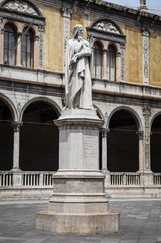 Verona, Italy – July 18, 2013: Dante Alighieri marble statue by Ugo Zannoni, situated at Piazza dei Signori (also known as Piazza Dante) in UNESCO listed historic city of Verona, Italy.