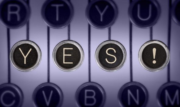 Close up of old typewriter keyboard with scratched chrome keys that spell out "YES!". Lighting and focus centered on "YES!". 