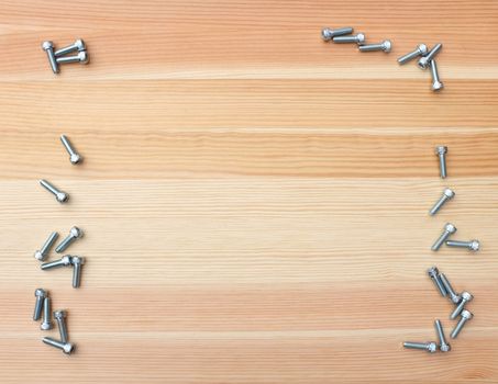 Socket head screws form a rough two-sided border on wooden background