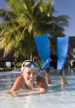Girl in snorkel gear relaxing in the shallows on a beach on the island of Manihi in French Polynesia in the South Pacific (Model Released)