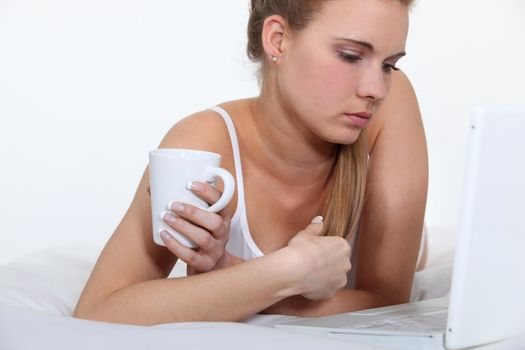 Woman laid on her bed using notebook