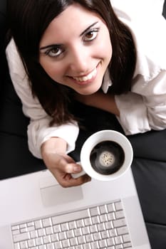 A young, hispanic adult girl with a Laptop and drinking coffee.