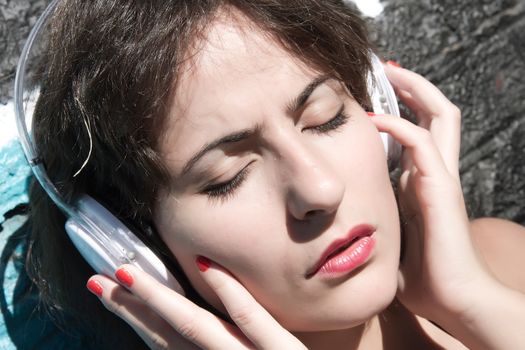 A vintage dressed girl listing to music in a urban environment.