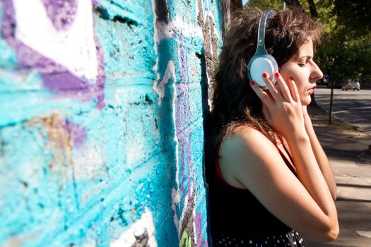 A vintage dressed girl listing to music in a urban environment.