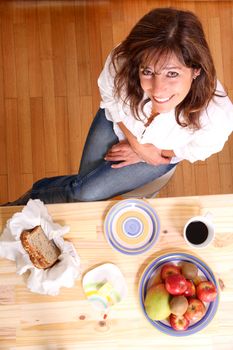 Portrait of a beautiful mature woman sitting in the kitchen. Focus on the Face.