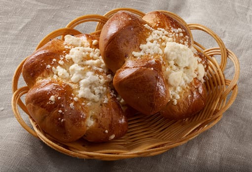 Two buns in the bread-basket on the tablecloth