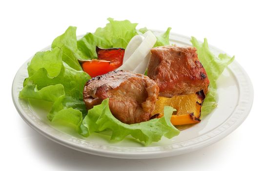 Hot roasted meat with onion, lettuce and pepper on the white plate