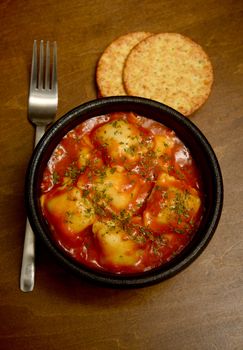 ravioli and red tomato sauce on wood background