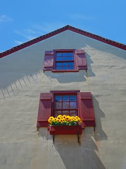 windows with red shutters and sunflowers in medeival village