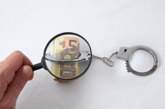 Financial Concept Loupe, Handcuffs and Money on a White Background