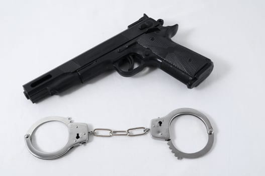 Criminality Concept Gun and Handcuffs on a White Background