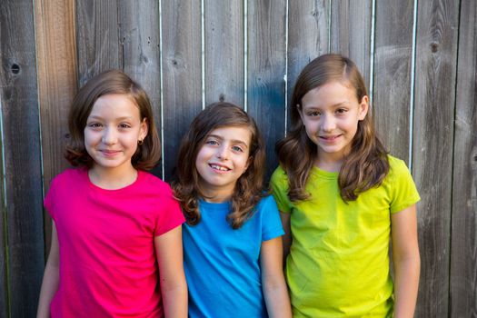 Sister and friends kid girls portrait smiling happy on gray fence wood backyard