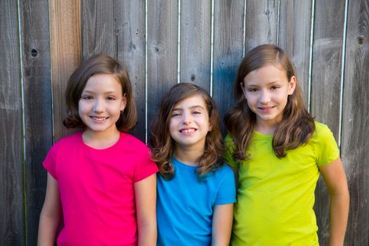 Sister and friends kid girls portrait smiling happy on gray fence wood backyard