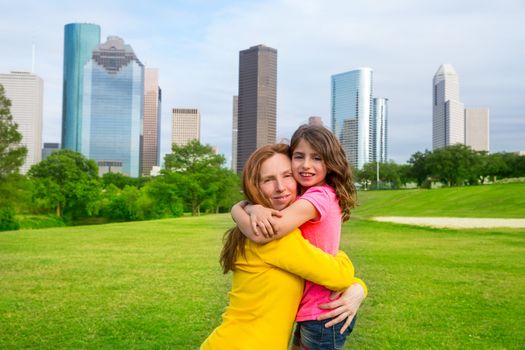 Mother and daughter happy hug in park at city modern skyline background