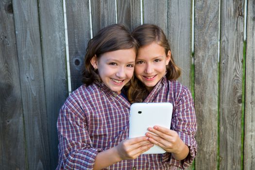 twin girls fancy dressed up pretending be siamese with dad shirt playing with tablet pc