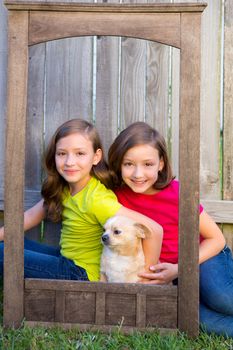 Twin sisters portrait with chihuahua dog on grunge wood border frame sitting on lawn