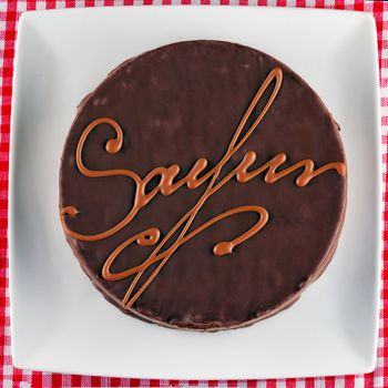 Sacher torte over a white plate, white and red cloth