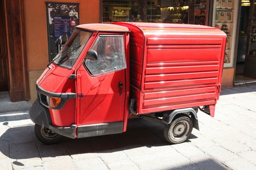 Bologna, Italy – July 17, 2013; Red Piaggio Ape vehicle on the street in Bologna, Italy.