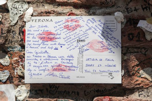 Verona, Italy – July 18, 2013: A letter to Juliet, the female protagonist of William Shakespeare's tragedy Romeo and Juliet, asking for love advice, sticked to the wall surrounding Casa di Giulietta (Juliet's House) in Verona, Italy.