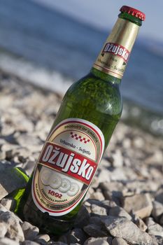 Crikvenica, Croatia – August 10, 2012: Bottle of Ožujsko, popular Croatian beer, on a pebbled beach.