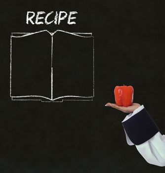 Chef with recipe book on chalk blackboard menu writing background