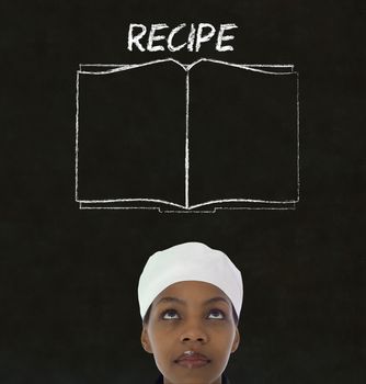 Chef with recipe book on chalk blackboard menu writing background